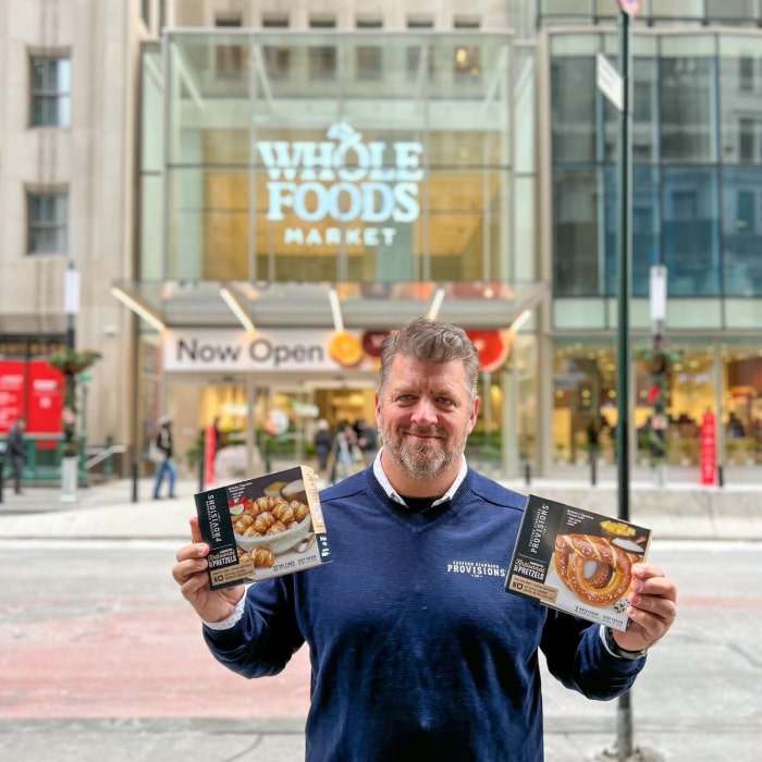 Man holding two box of pretzels in front of wholefoods